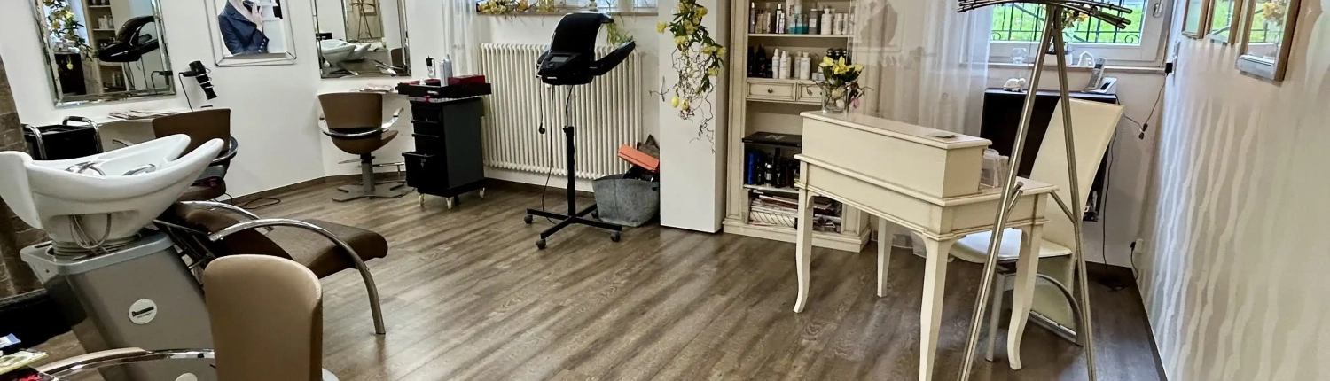 Großzügiger und moderner Innenraum von Tanjas Haarstudio Eriskirch am Bodensee mit Friseurstühlen, Spiegeln und Fach für Haarpflegeprodukte.