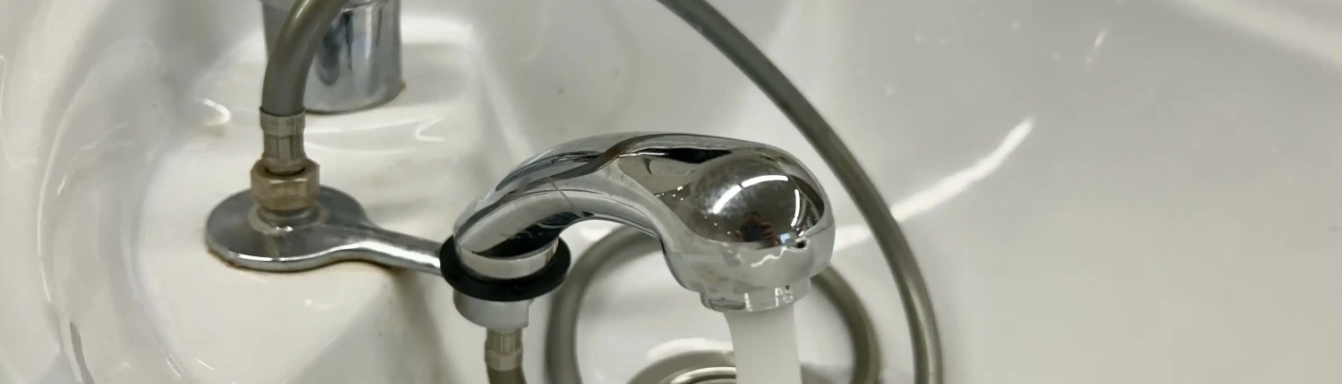 Weißes Friseurwaschbecken mit fließendem Wasser und verchromten Armaturen in Tanjas Haarstudio und Zweithaarstudio.